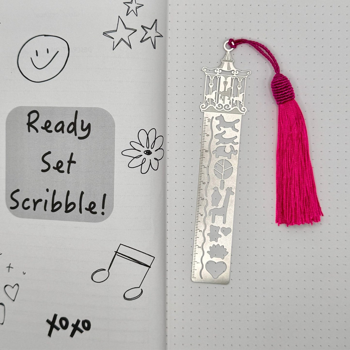Metal bookmark with tassel on a gray background with doodles