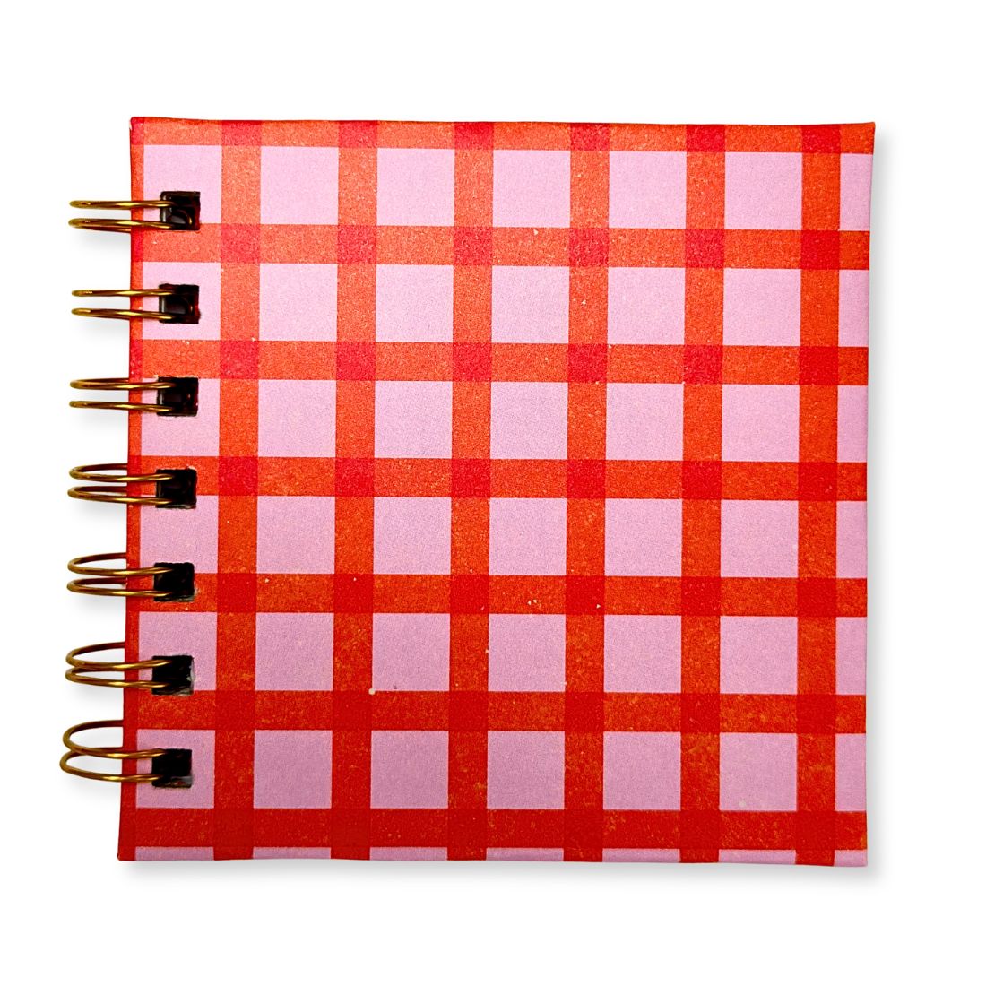 Front view of a handmade Love To Scribble square mini notebook with a vibrant pinkish-purple and orange checkered square pattern and gold spiral binding.
