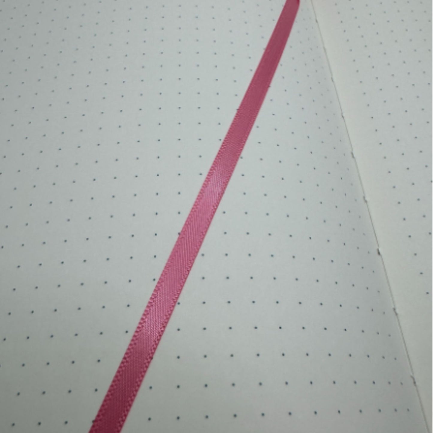 Sheet of paper with dotted and a pink tassel on a off white paper