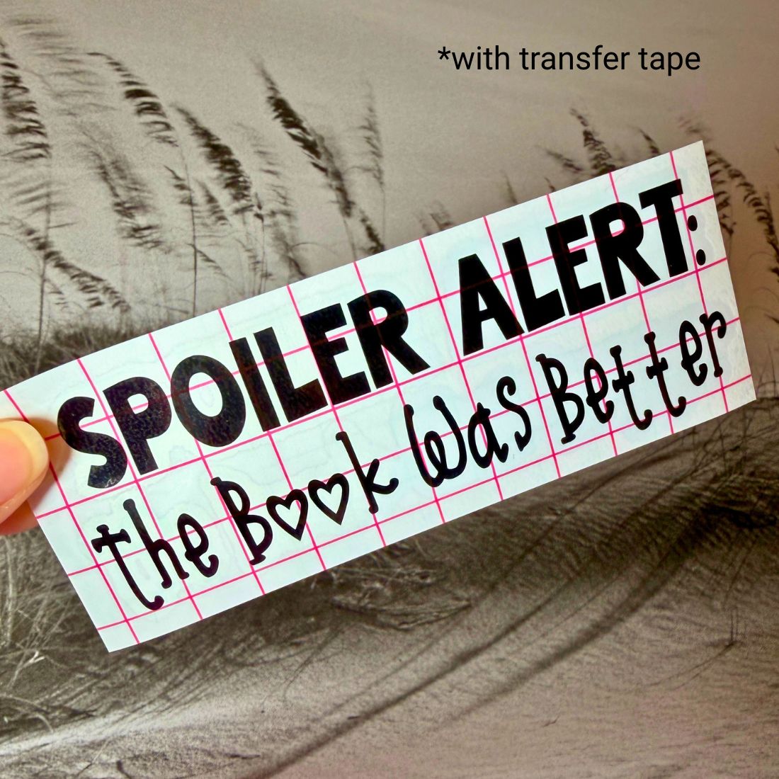 Close-up of the bookish vinyl decal with a red grid transfer tape overlay ready for application.